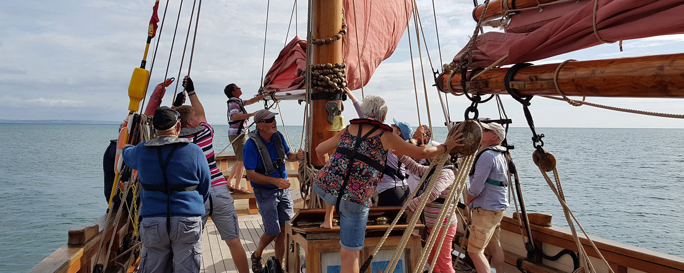 Pilgrim crew and guests hoisting the sails